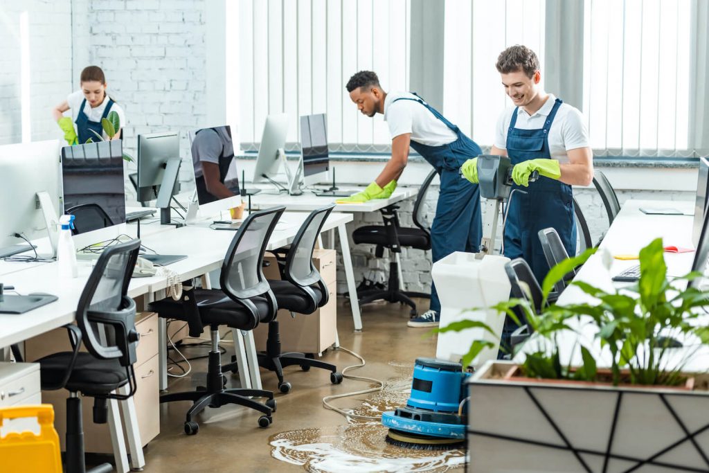 Reinigungsteam reinigt Schreibtische in einem Büro